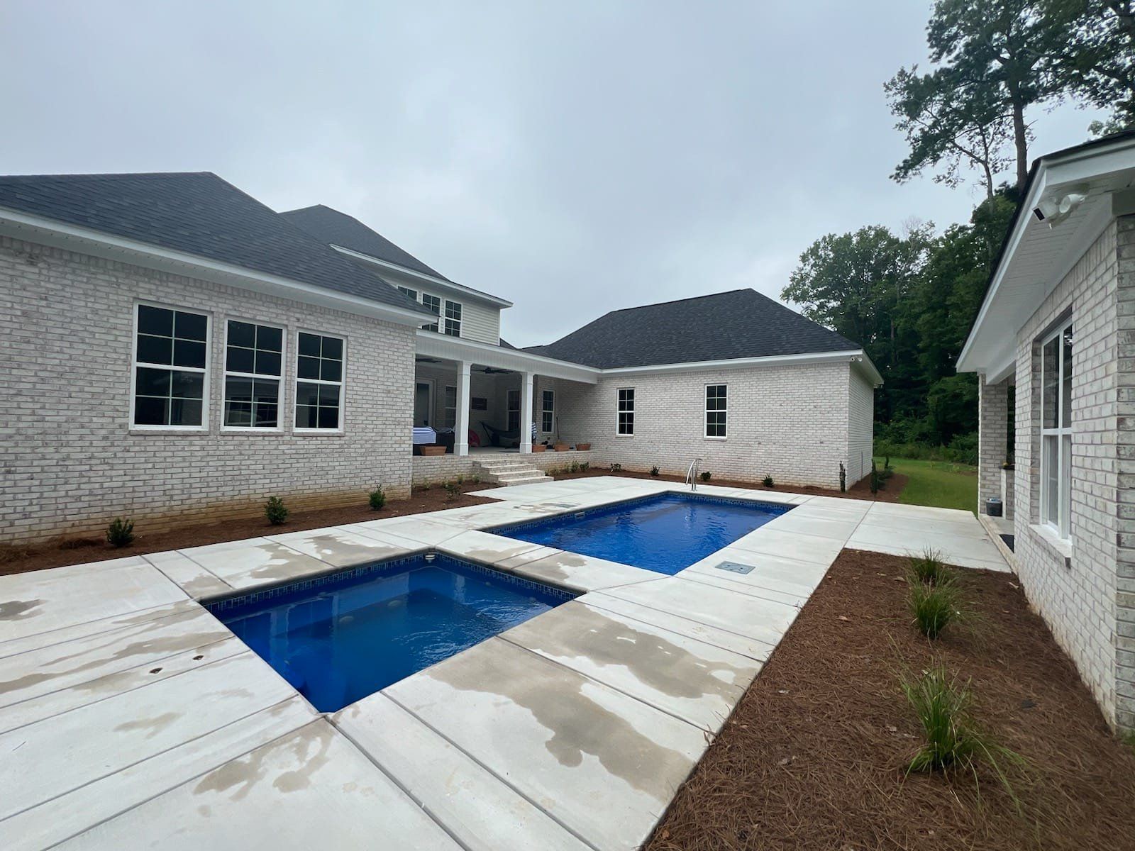 There are two swimming pools in the backyard of a house.