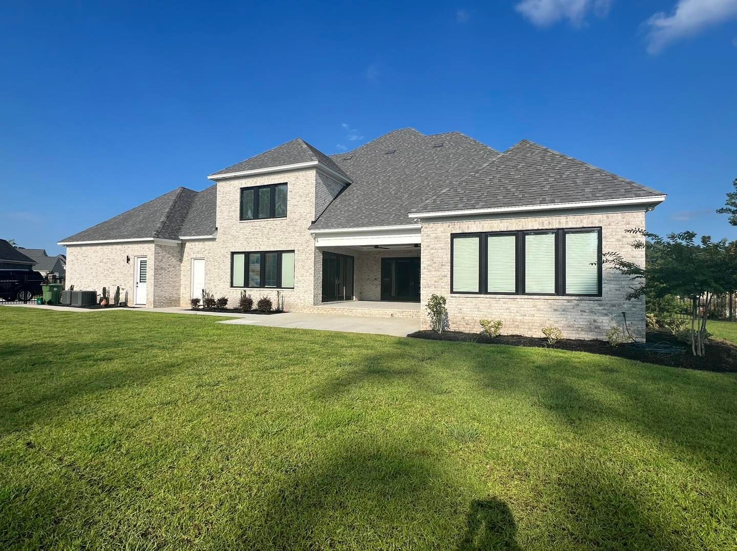 A large house with a lot of windows is sitting on top of a lush green lawn.
