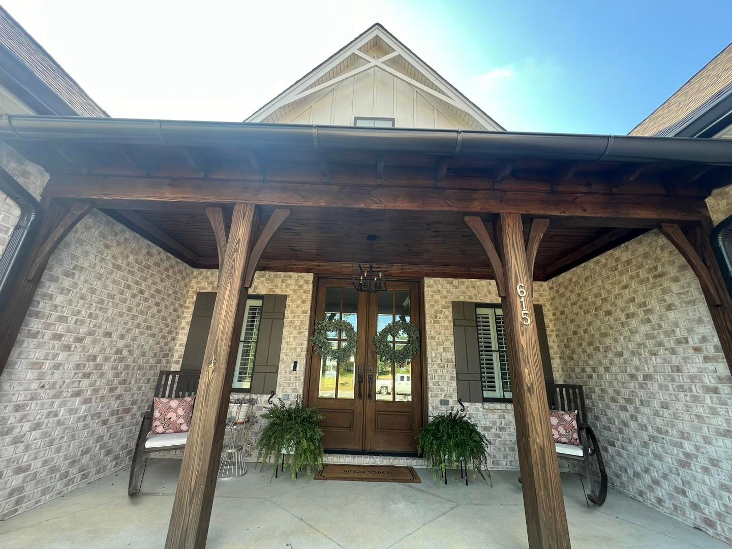 The front of a house with a wooden porch and a bench.