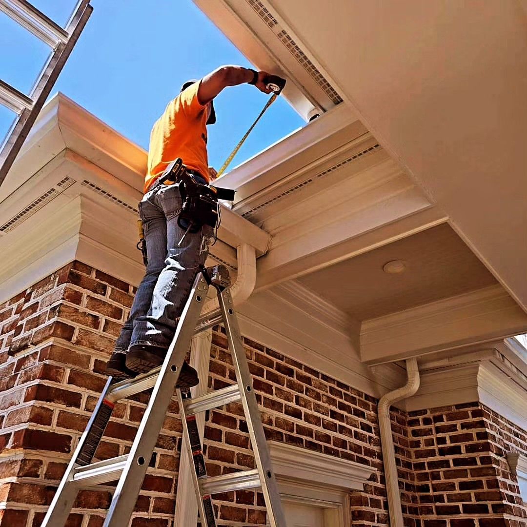 A man standing on a ladder measuring a gutter