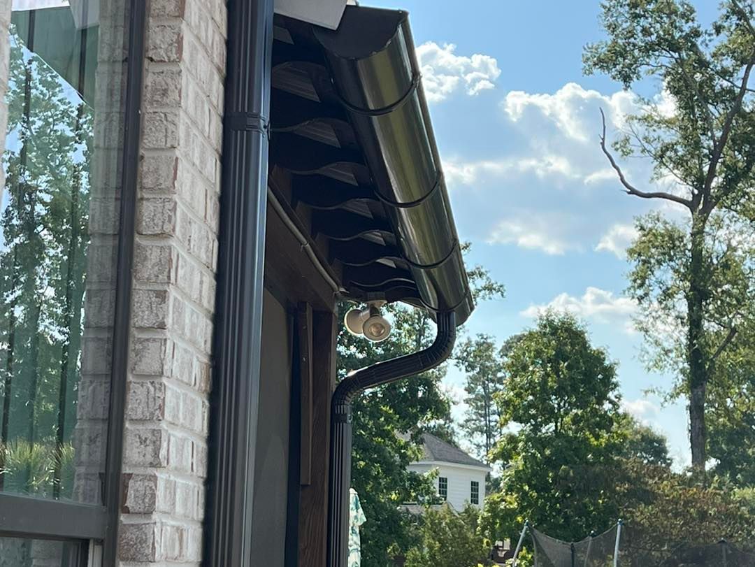 A brick building with a black gutter on the side of it.