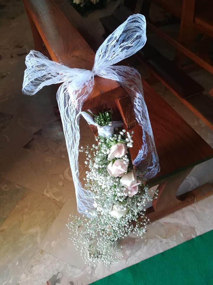 Decorazione per banchi nuziali con fiori, rose rosa e gypsophila legati con pizzo bianco.