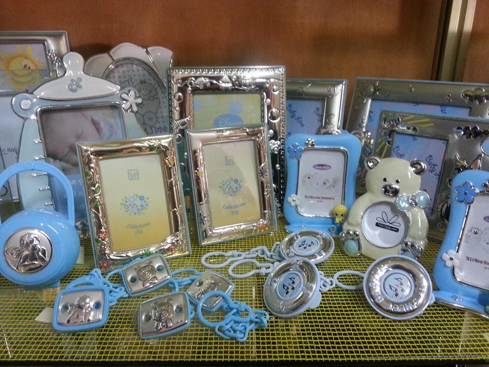 Cornici per foto a tema neonati color argento e blu e fermaciucci su uno scaffale espositivo.