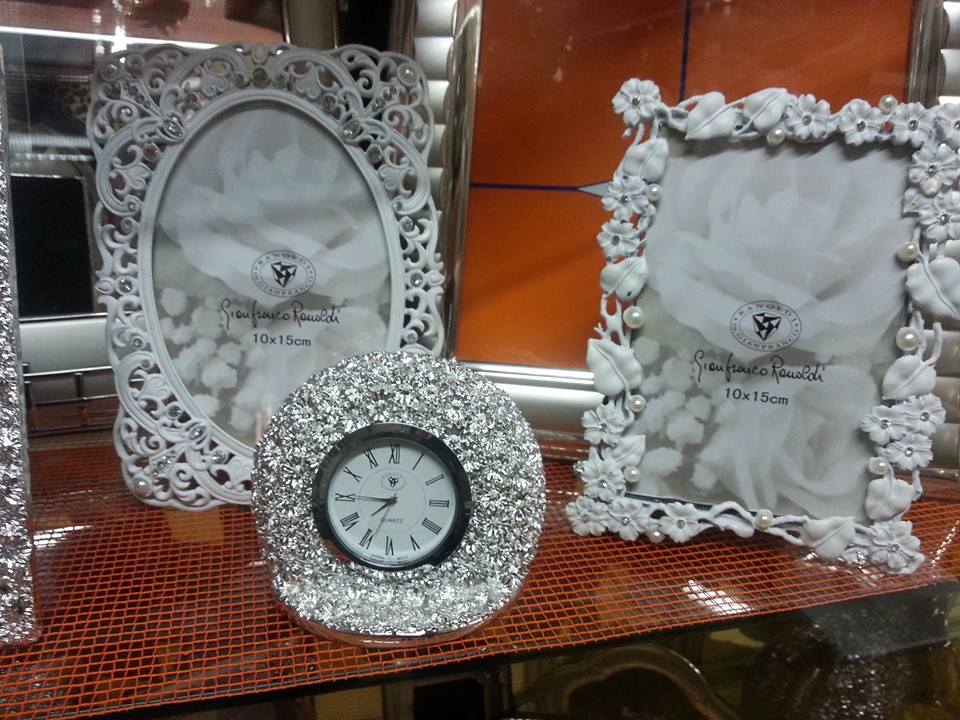 Eleganti cornici bianche e un orologio con decorazioni in cristallo in mostra.