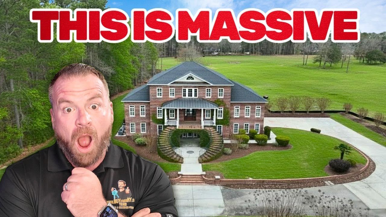 Man with surprised expression in front of a large brick house with green lawn. Text