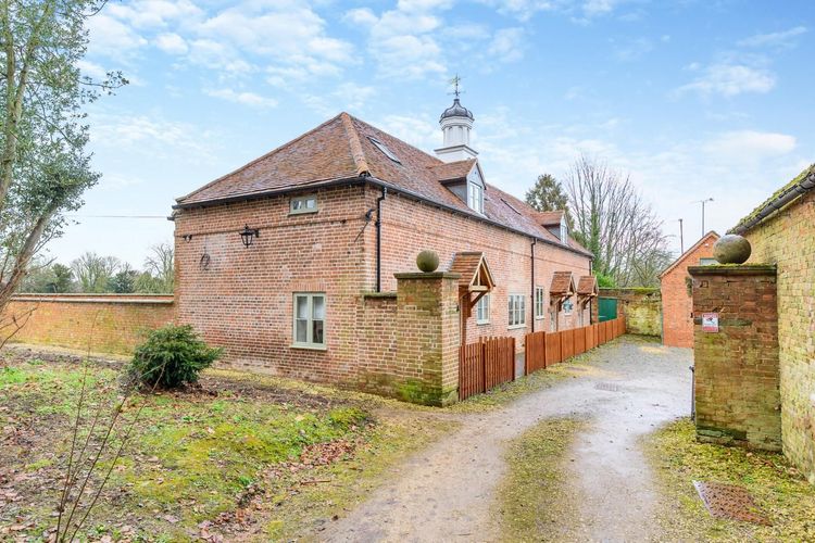 A small brick house with a tower on top of it is sitting next to a dirt road.