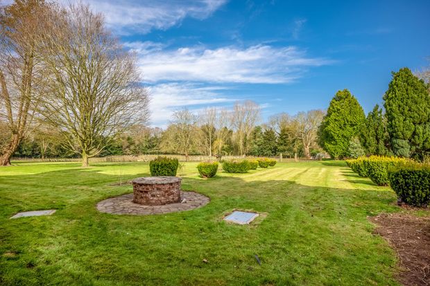 There is a fire pit in the middle of a lush green field.