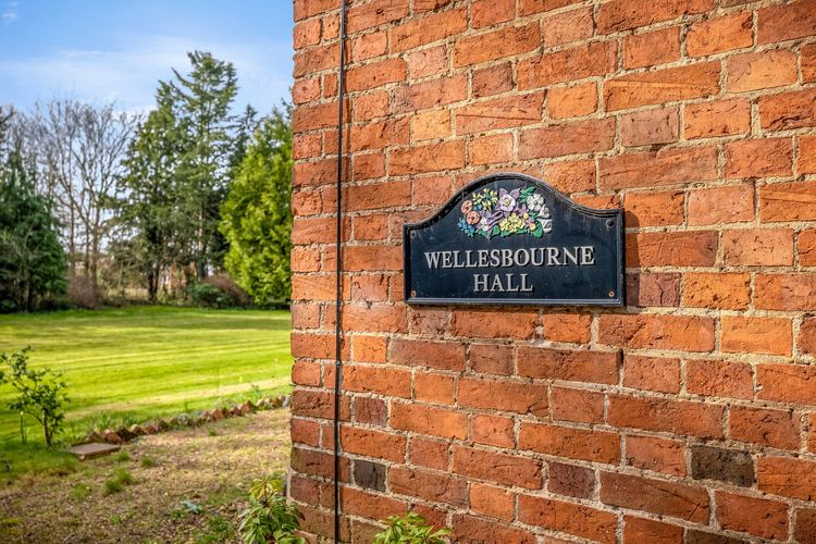 A brick wall with a sign on it that says wellsbourne hall.