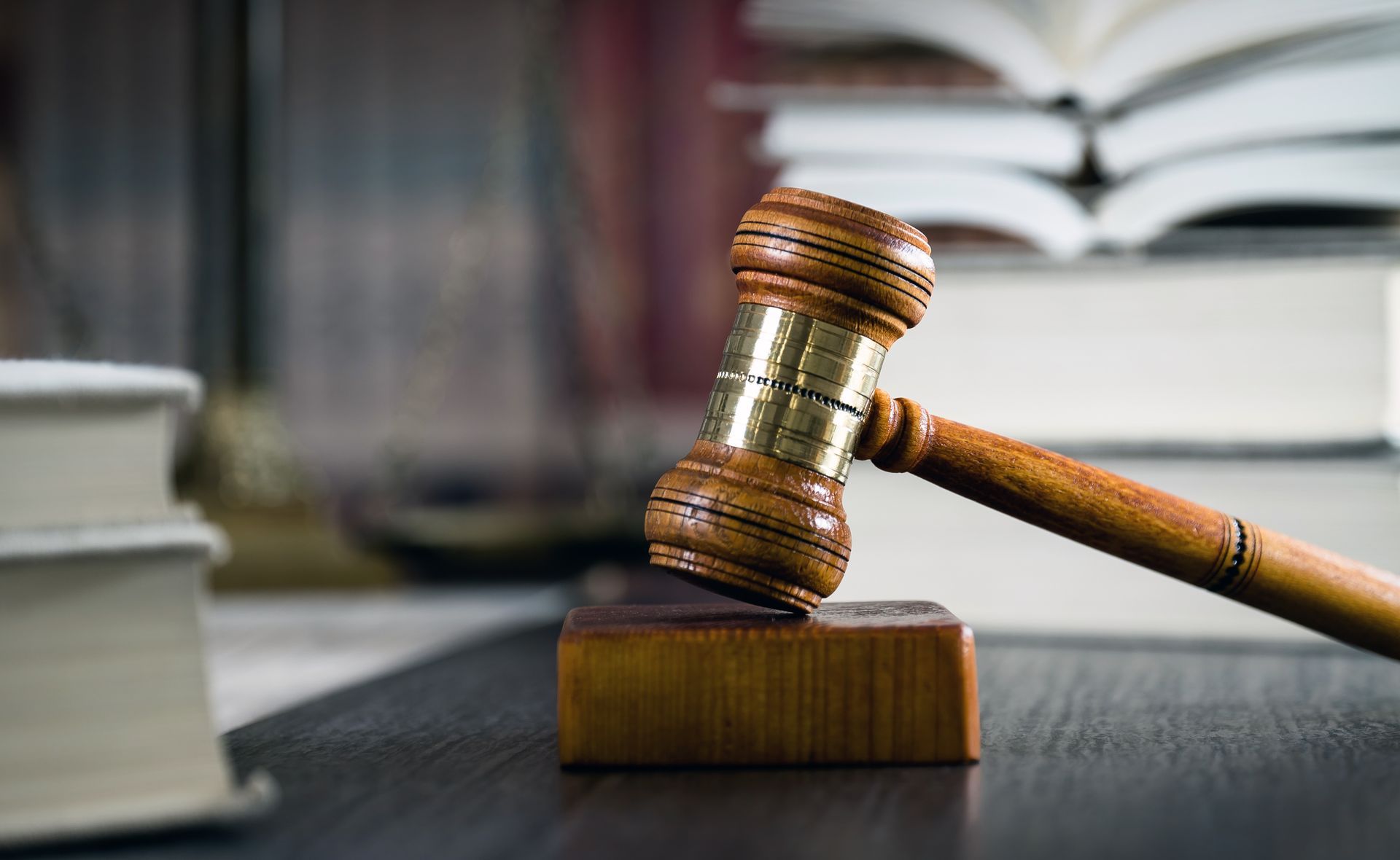 A wooden judge 's gavel is sitting on a table in front of a stack of books.