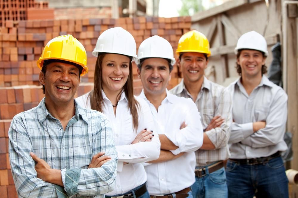 Construction Workers, Mixed Gender, Wearing Hard Hats, Smiling, Arms Crossed, Posing at A Building Site — Joy Hire Compressor Hire & Maintenance in Paget, QLD
