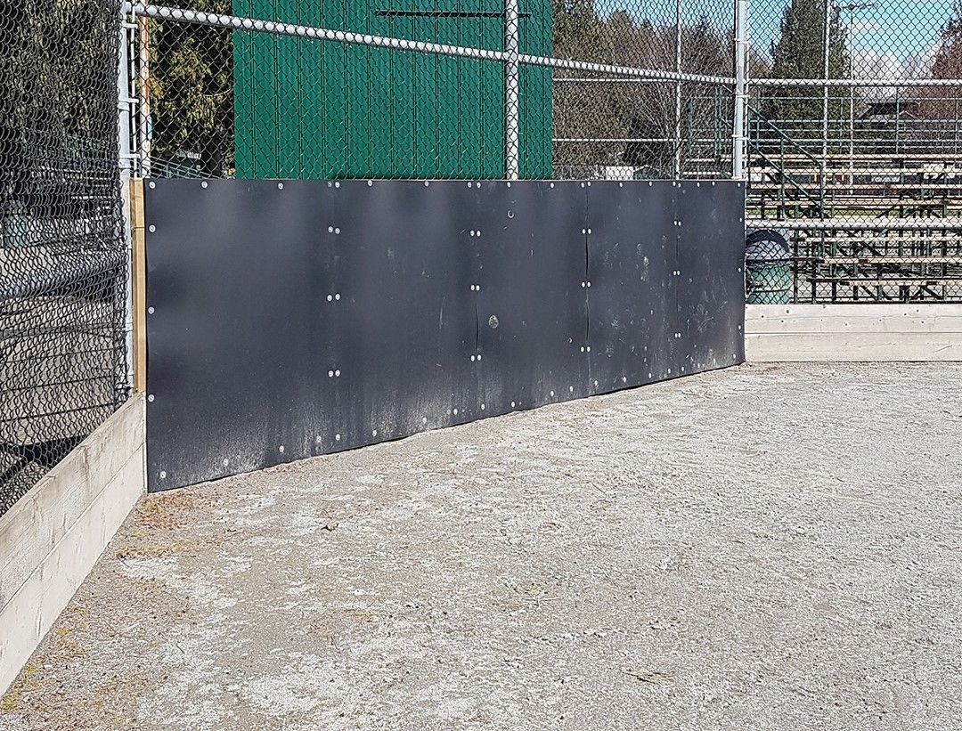 A black fence surrounds a gravel field next to a chain link fence.