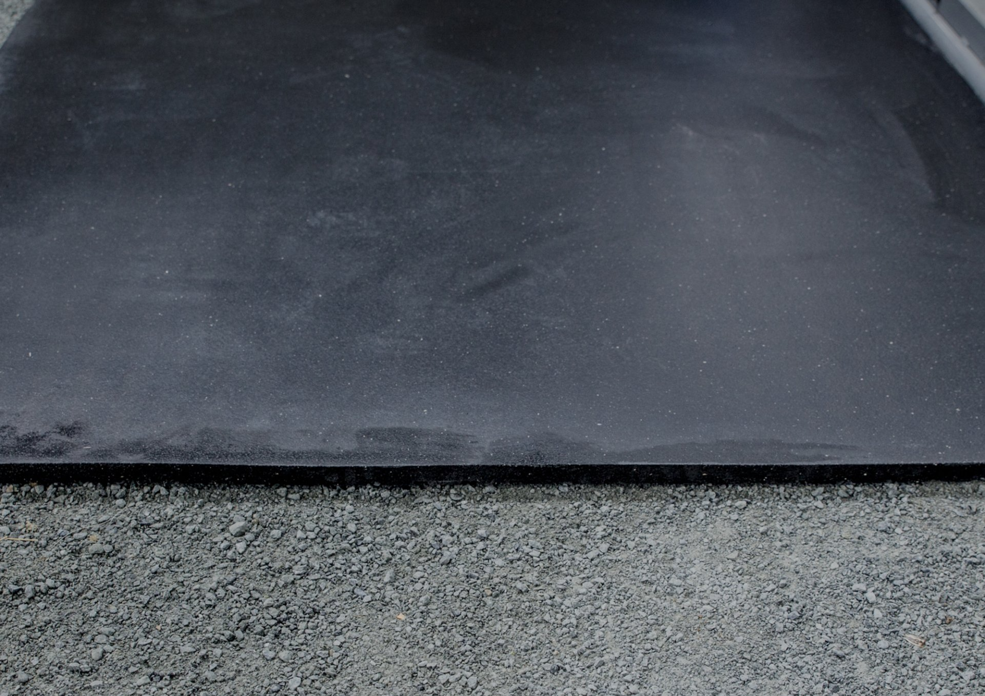 A black rubber mat is sitting on top of a gray carpet.