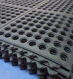 A close up of a stack of rubber mats with holes in them.