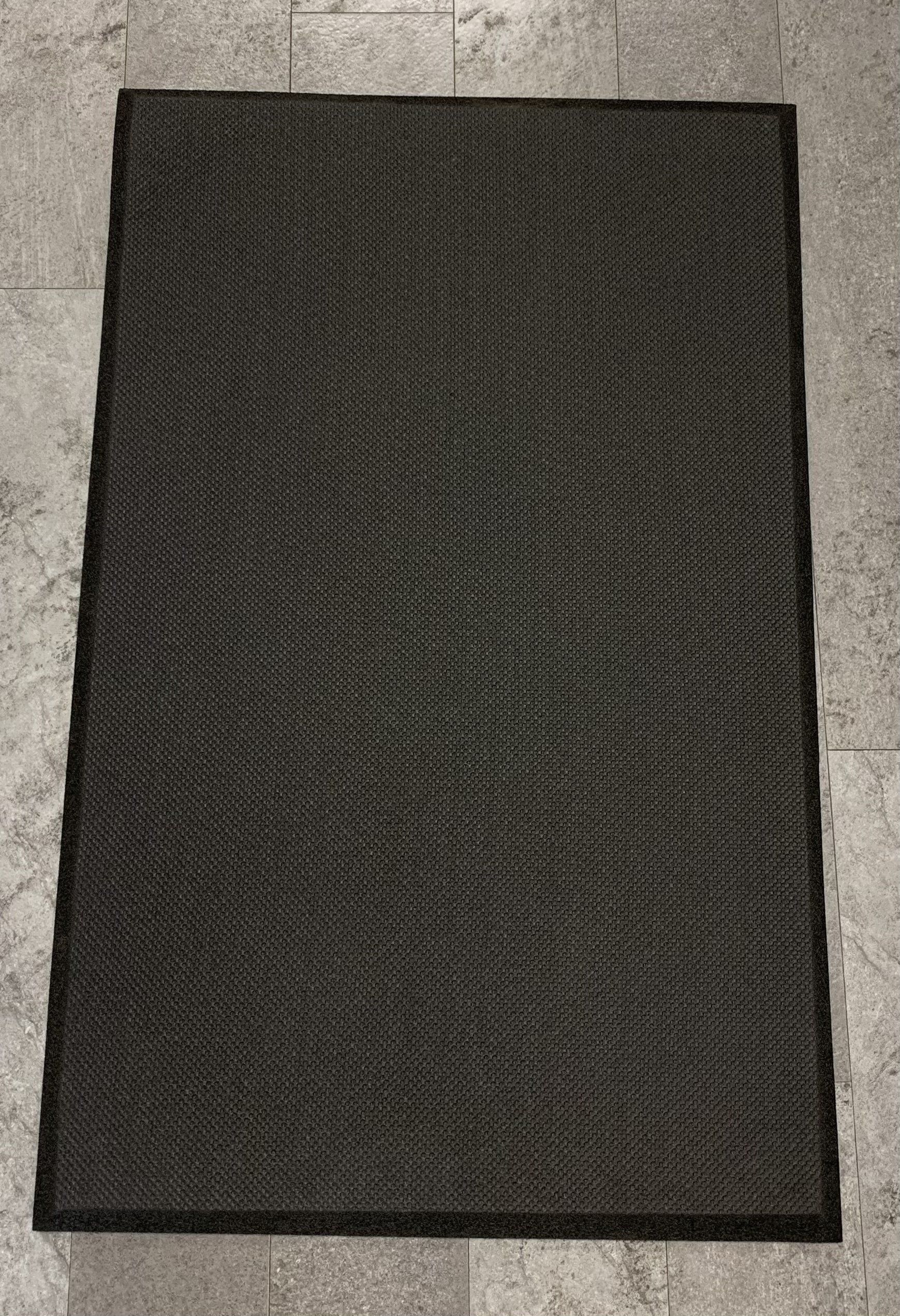 A black rug is sitting on a tiled floor.