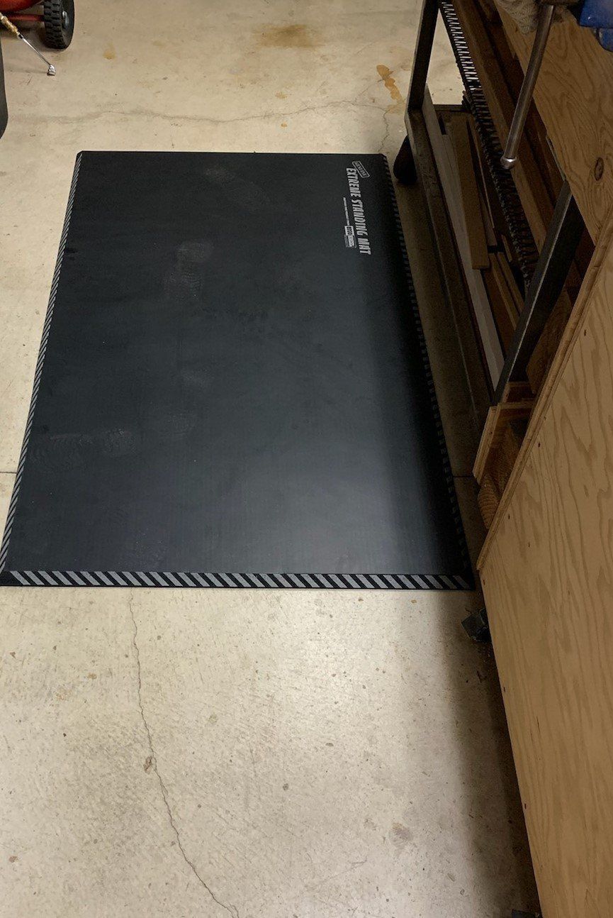 A black mat is sitting on the floor next to a wooden table.