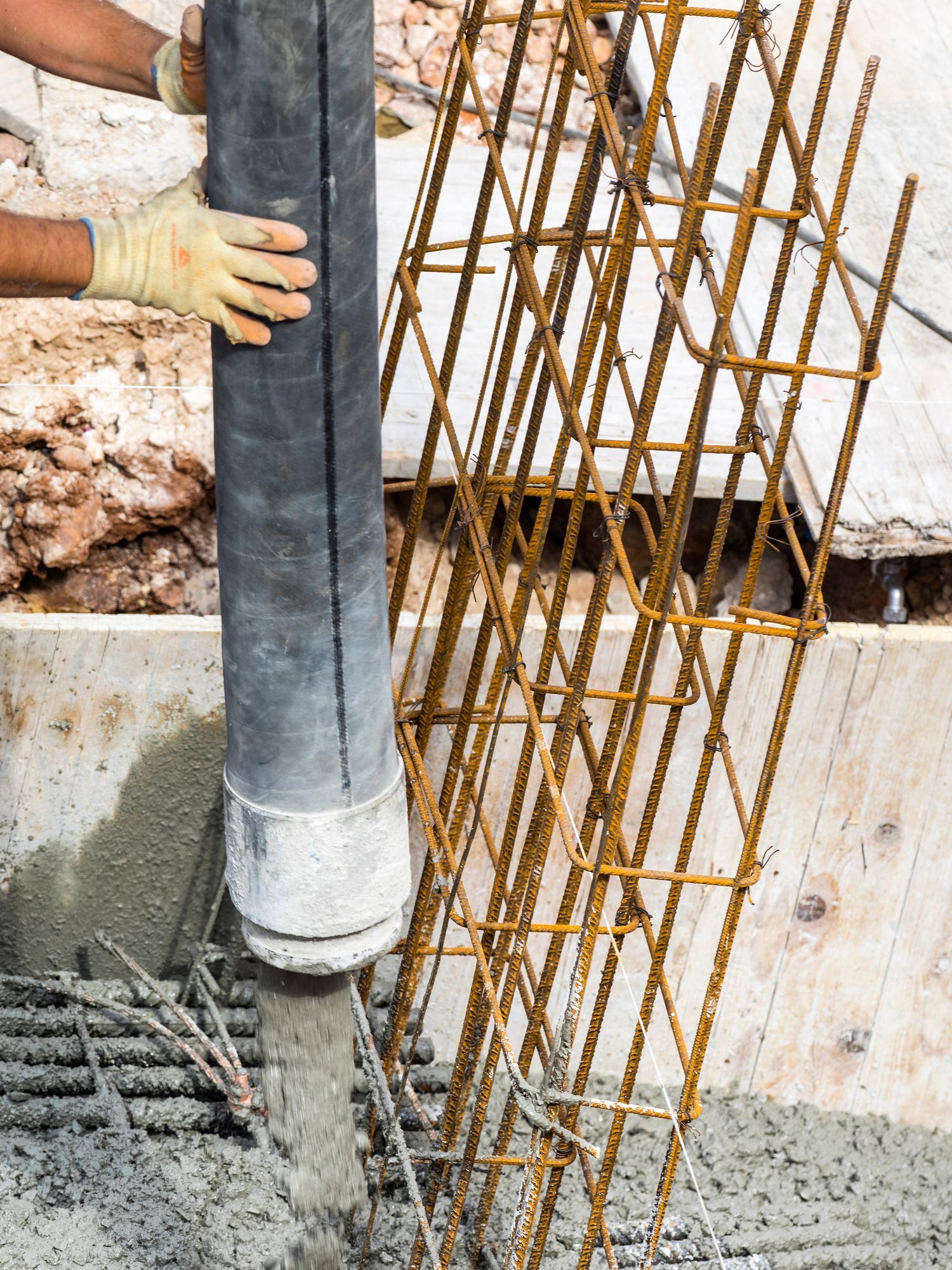 A man is pouring concrete into a hole in the ground.
