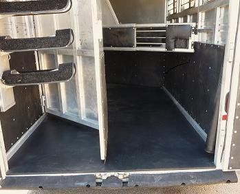 The inside of a horse trailer with the doors open and stairs.