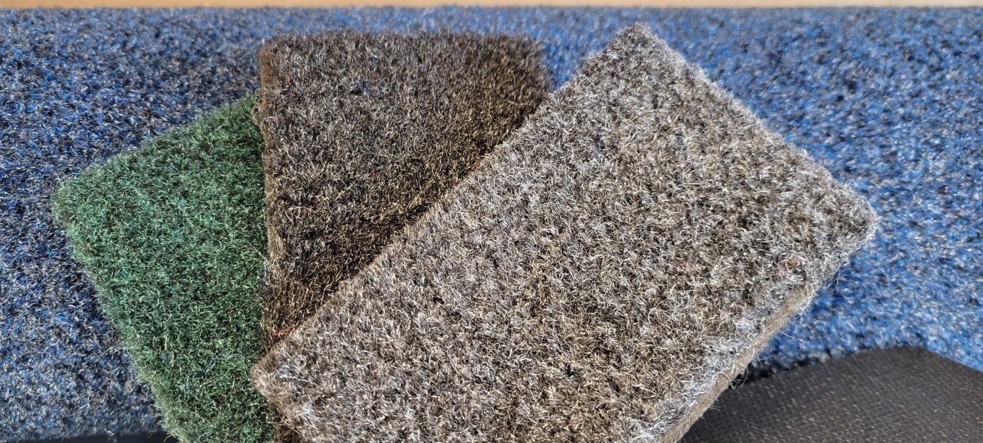 Four pieces of carpet are stacked on top of each other on a table.