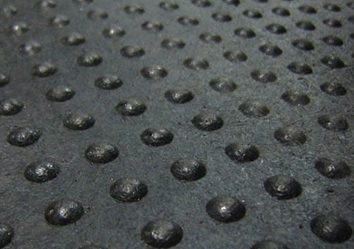 A close up of a black rubber mat with holes in it.