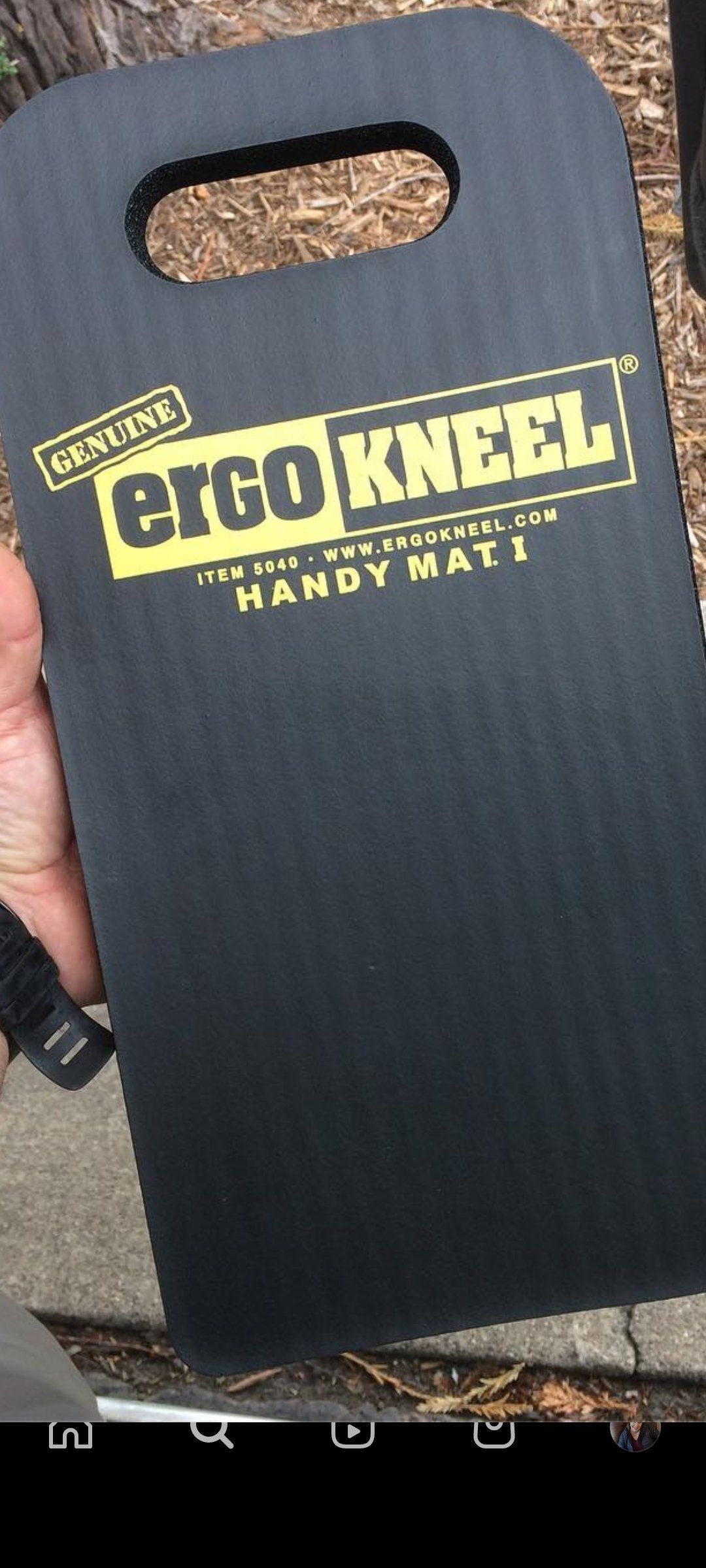 A person is holding a black ergo kneel handy mat.