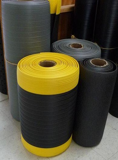 A bunch of rolls of rubber mats are stacked on top of each other.