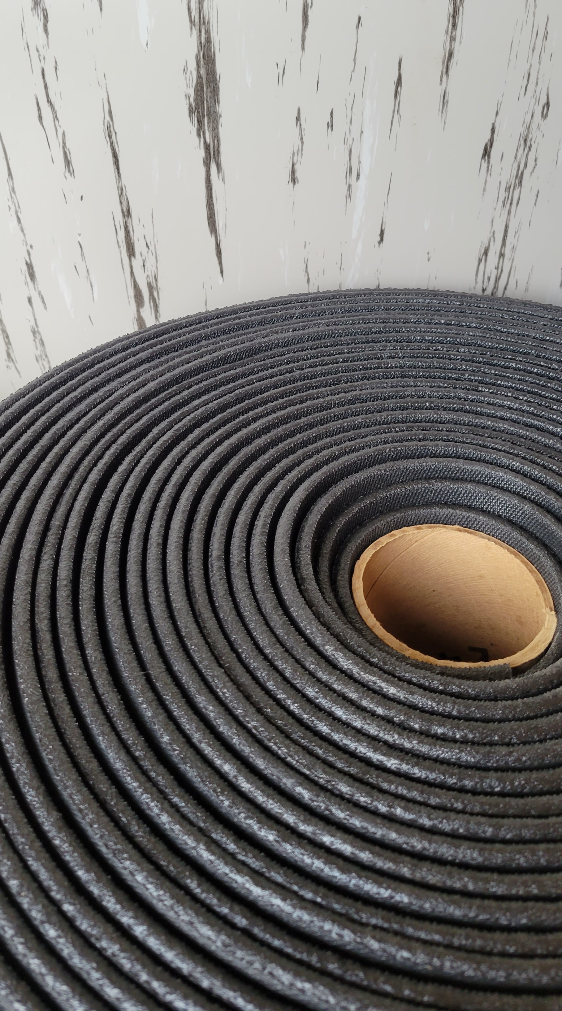 A close up of a roll of black rubber mat with a hole in the middle.