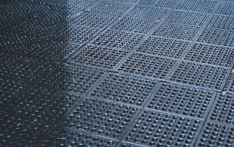 A close up of a black rubber mat with holes in it.