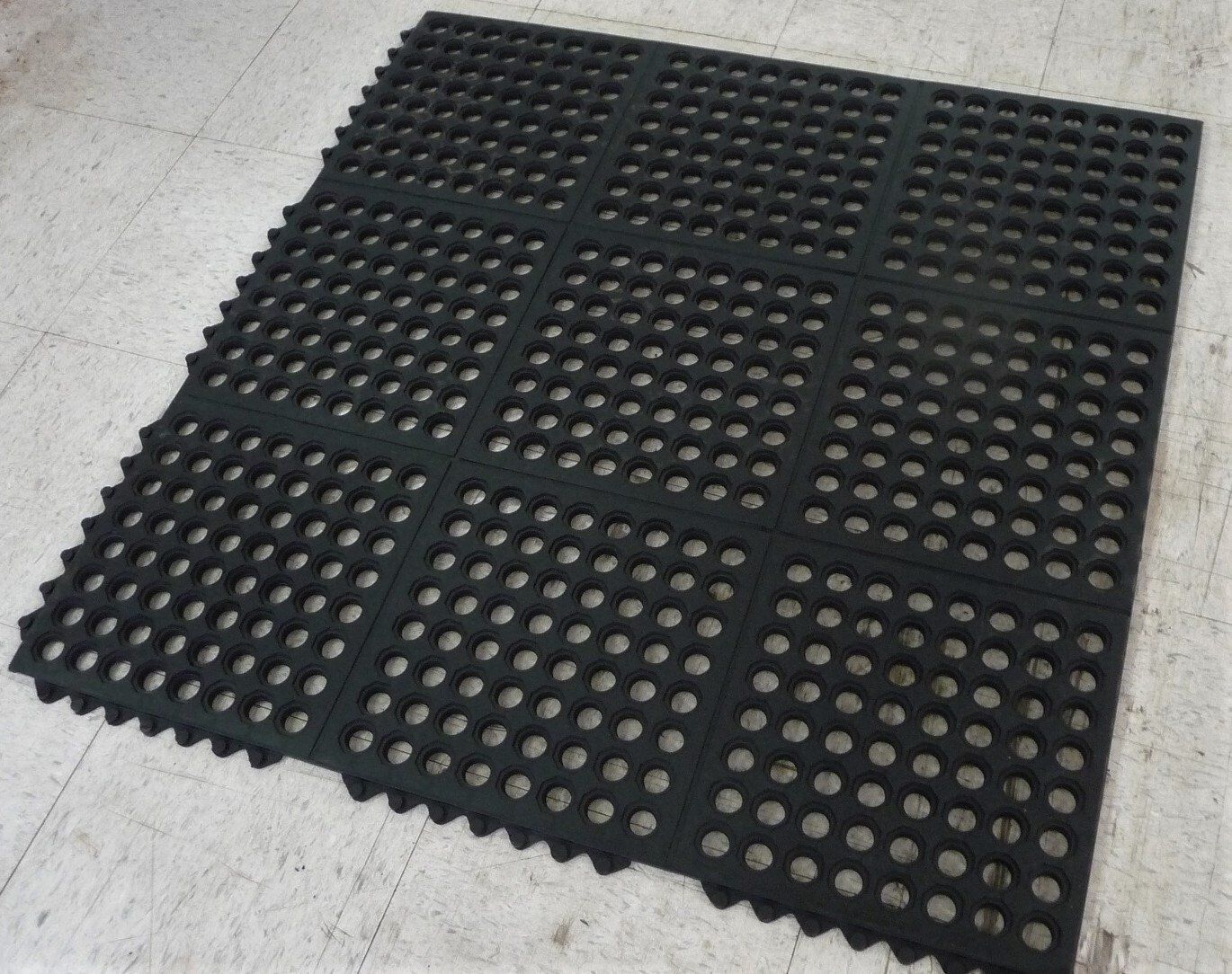 A black mat with holes in it is laying on the floor