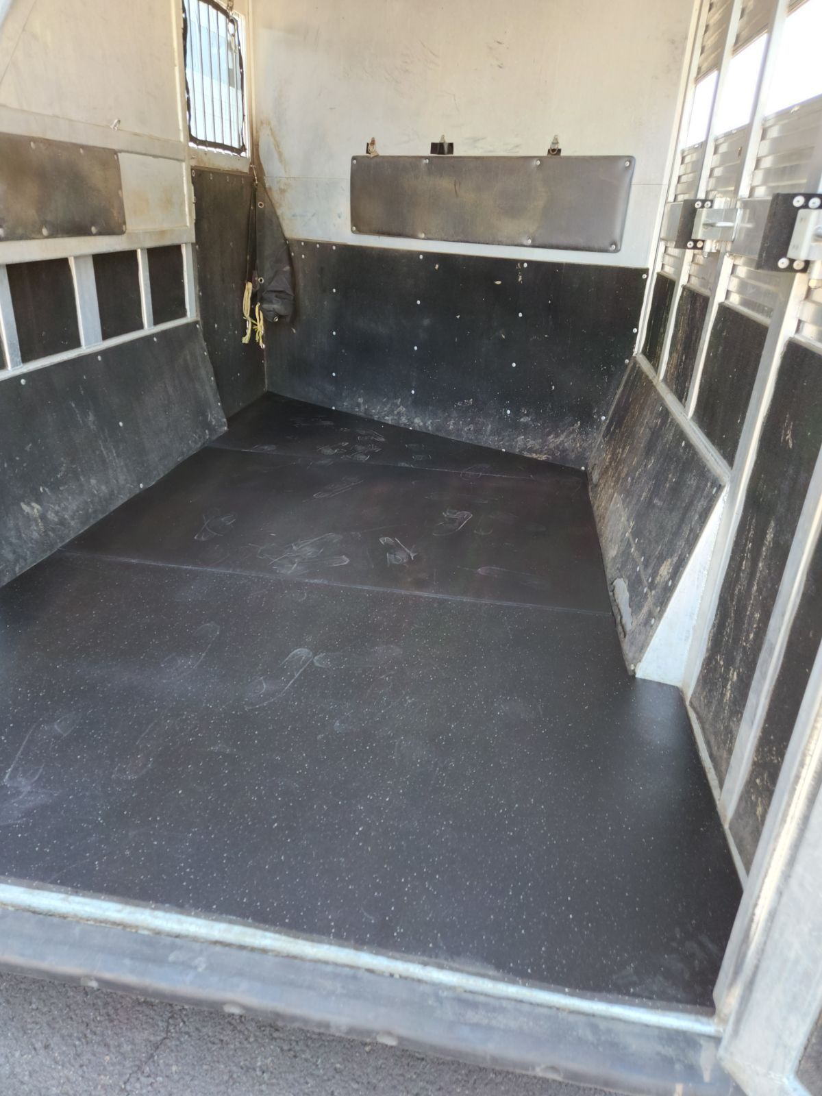 The inside of a horse trailer with a black floor