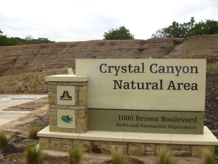 Sign for Crystal Canyon Natural Area at 1000 Brown Boulevard, featuring a park logo.