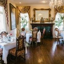 Elegant dining room with tables set for a meal, including a grand mirror, artwork, and windows.