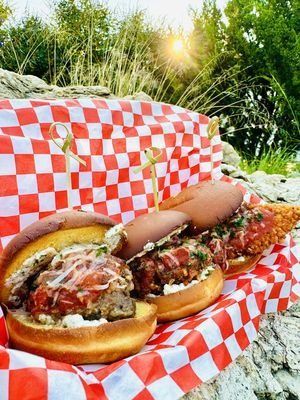 Three sliders in a red and white checkered basket; meatballs, and fried chicken visible.