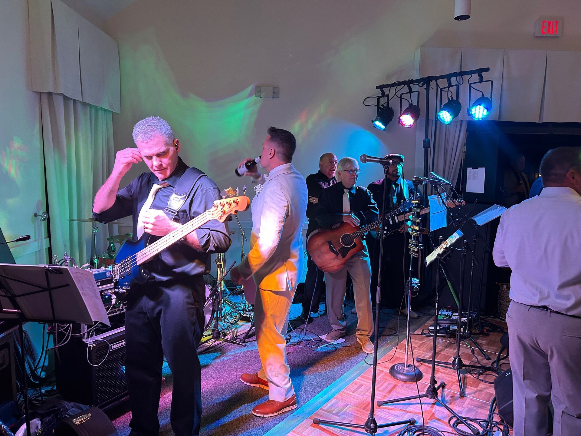 Band performing on stage with colorful lights, instruments, and microphones.