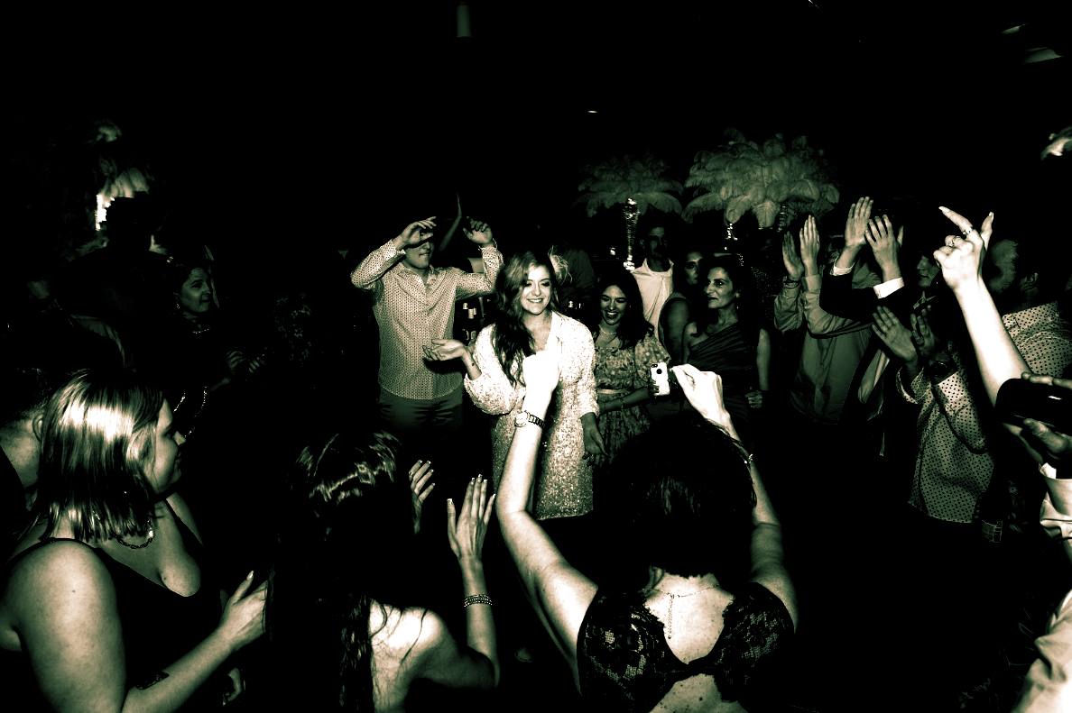 People dancing in a dark room. Arms raised, celebrating, and enjoying the music.