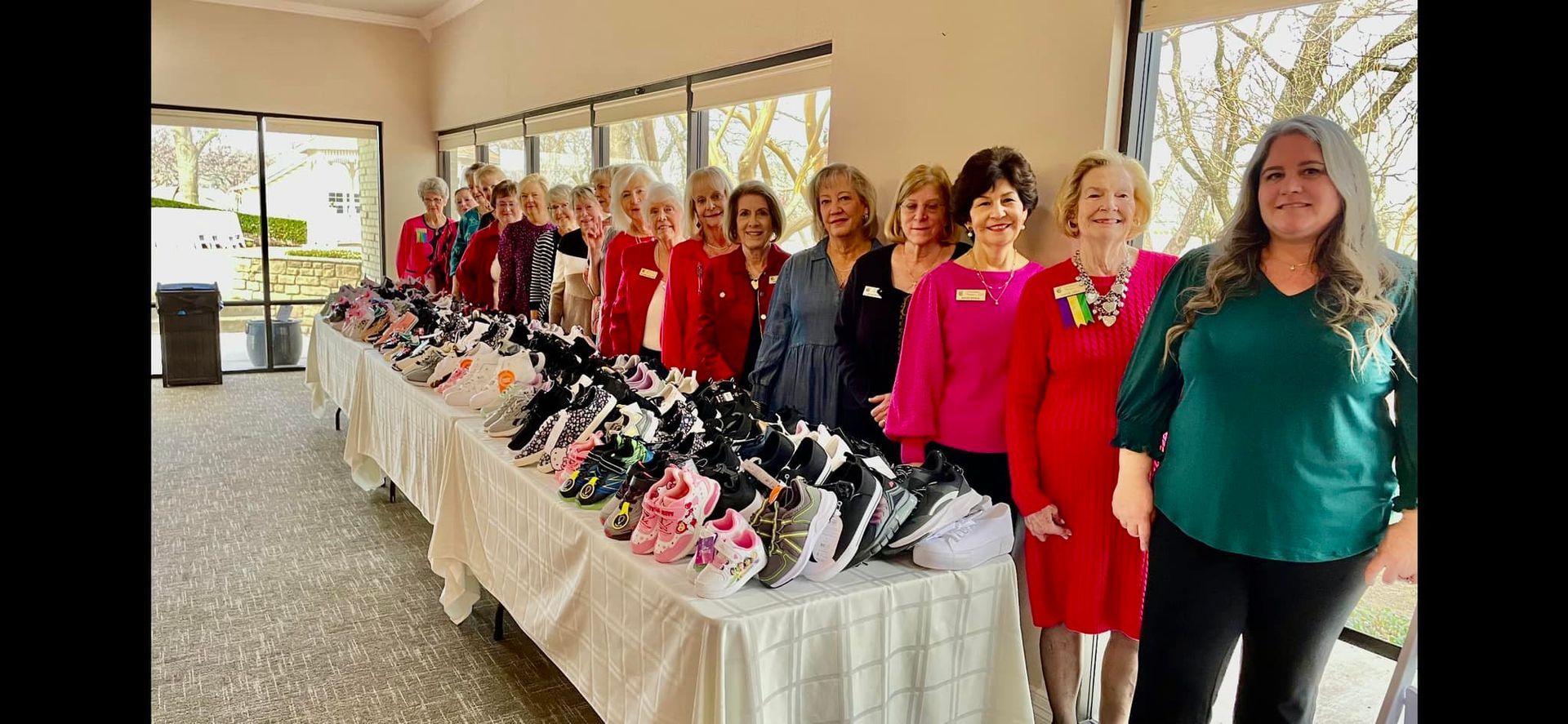 A group of women are standing in front of a table filled with shoes.