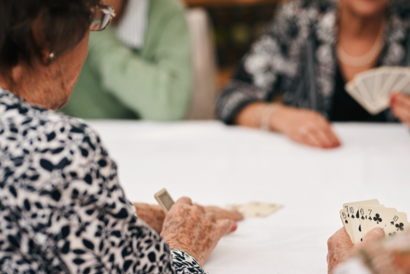 A group of elderly people are playing cards at a table.