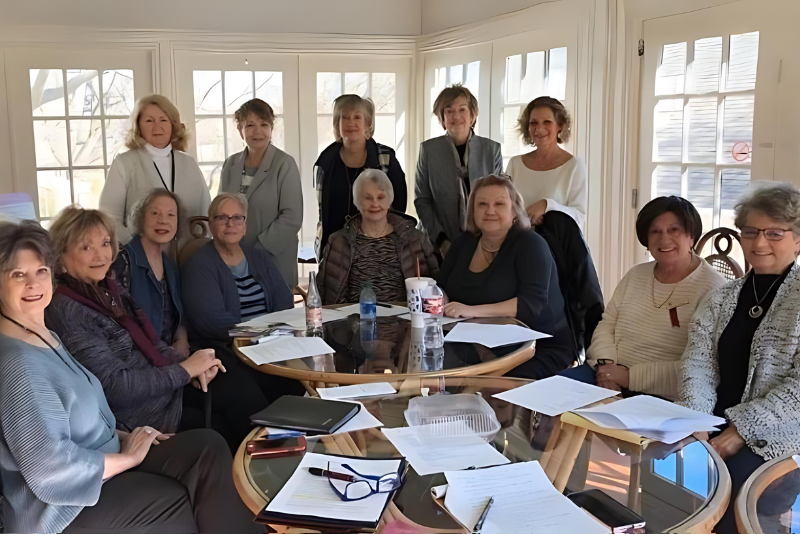 A group of women are sitting around a table with papers on it.