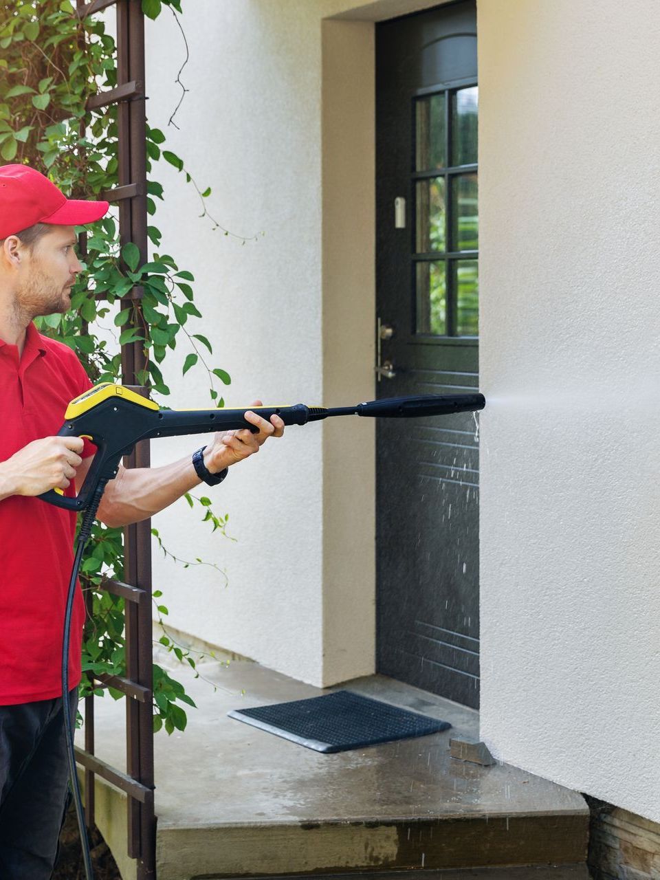 worker washing the wall near the front door with a high pressure gun