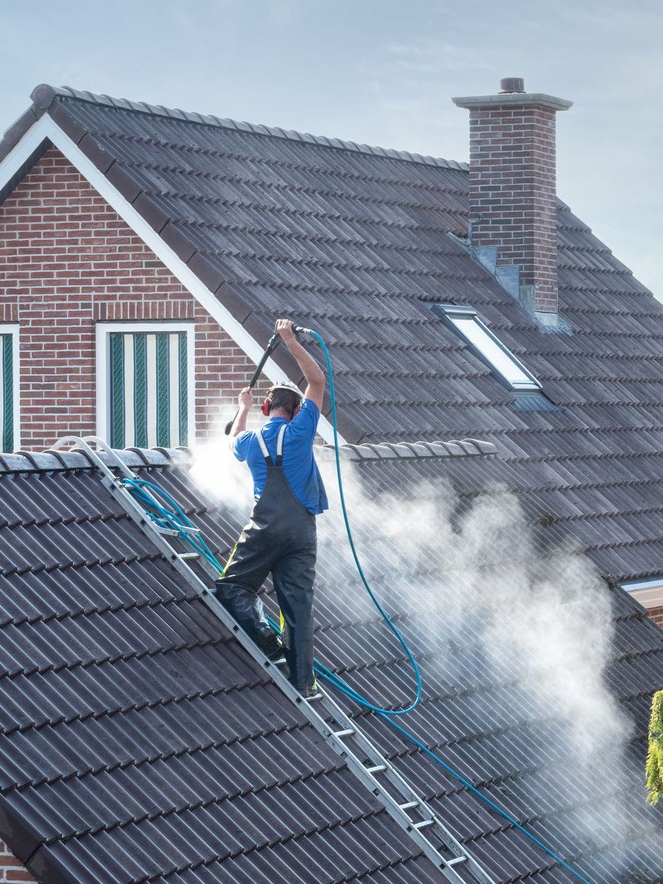 worker washing the roof with a high pressure gun