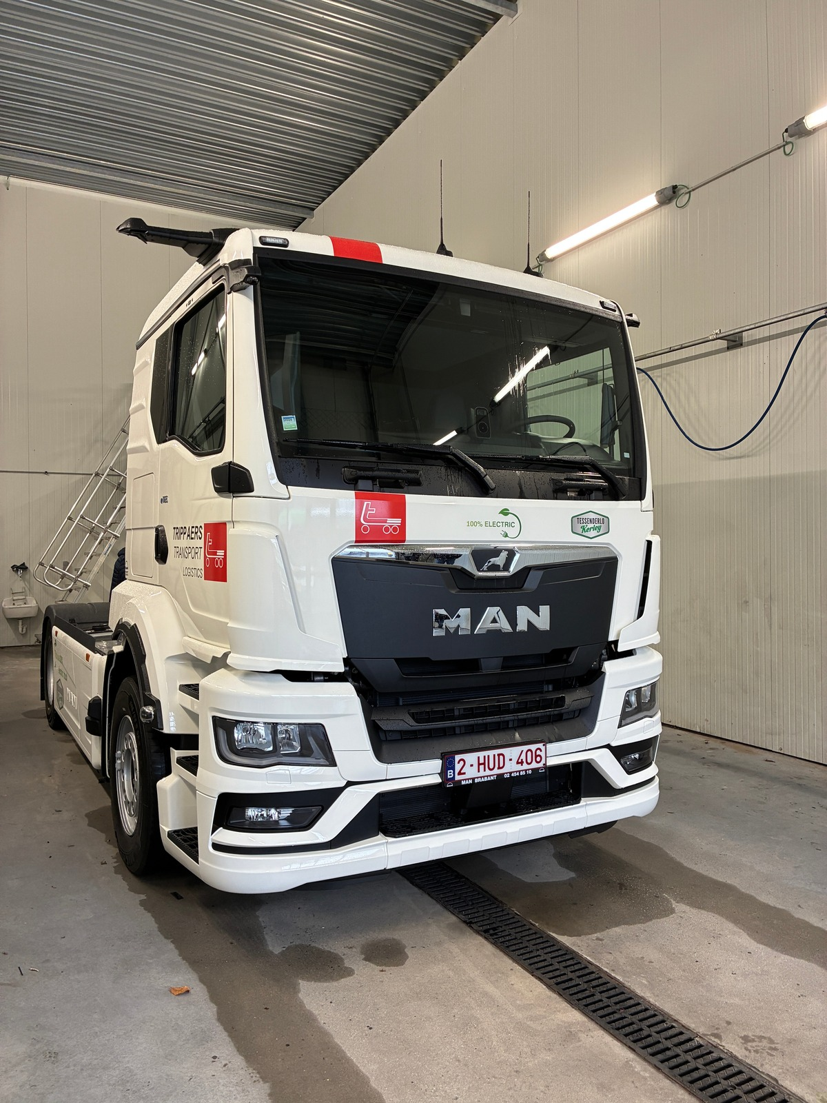 Witte etruck MAN-vrachtwagen geparkeerd in een garage. Zwarte grille, koplampen en red line