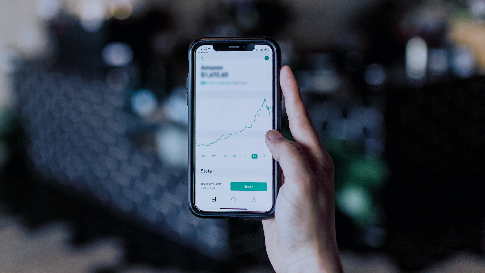 A person is holding a cell phone with a graph on the screen.