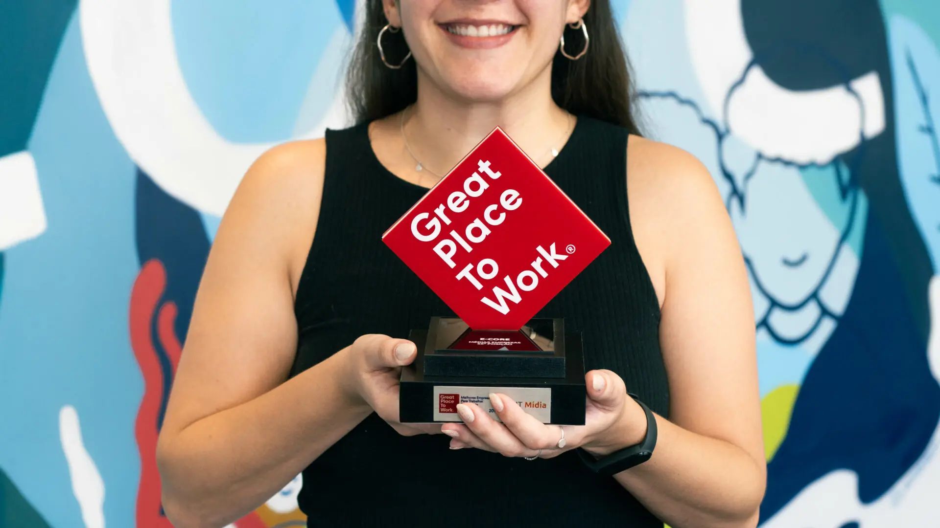 A woman is holding a trophy that says `` great place to work ''.