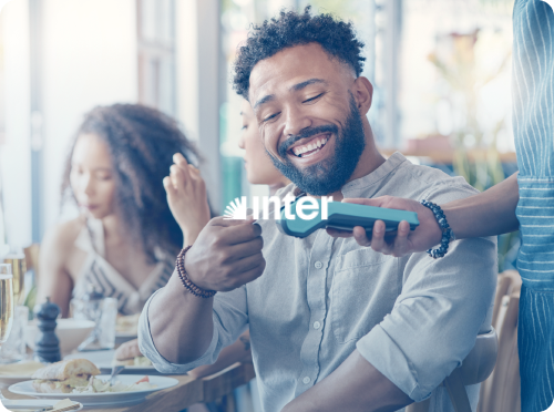 Um homem está sentado à mesa de um restaurante segurando um cartão de crédito.