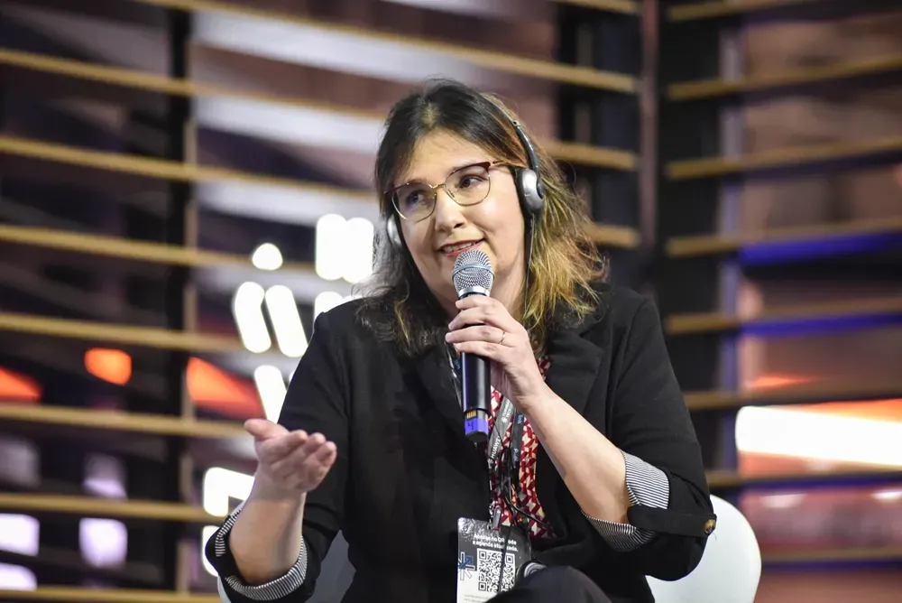A woman wearing headphones is sitting in front of a microphone.