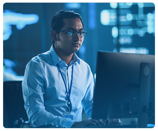 Um homem está sentado em frente a um monitor de computador.