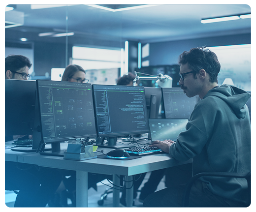 Um homem está sentado em uma mesa em frente a um computador.