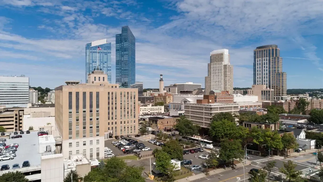 Downtown Stamford, Connecticut skyline featuring modern high-rises and older buildings under a blue sky.
