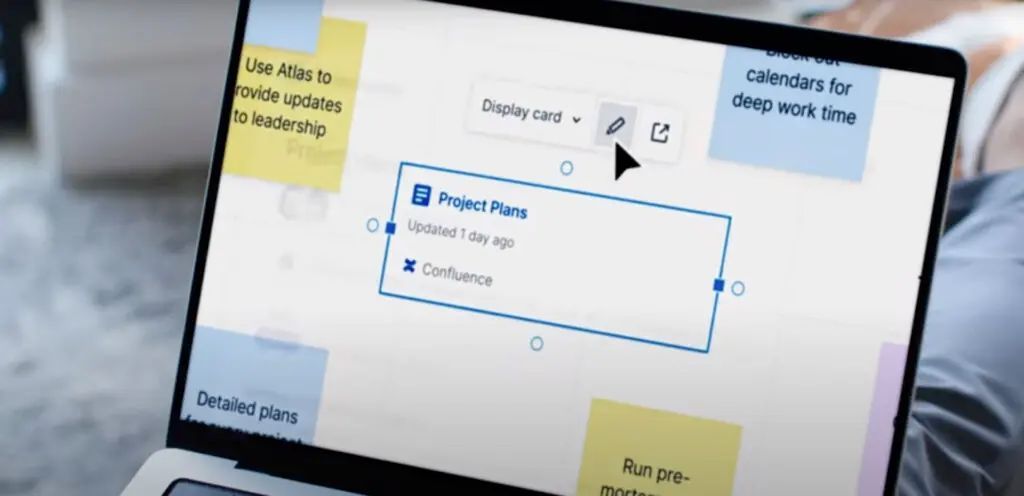 A person is using a laptop computer with sticky notes on the screen.