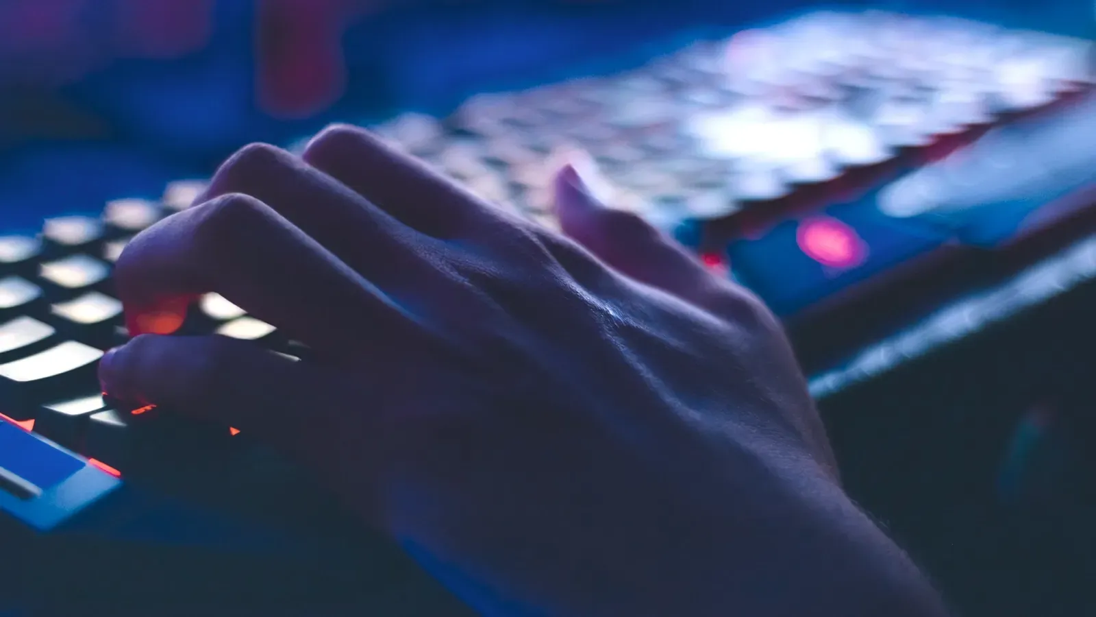 A person is typing on a computer keyboard in the dark.