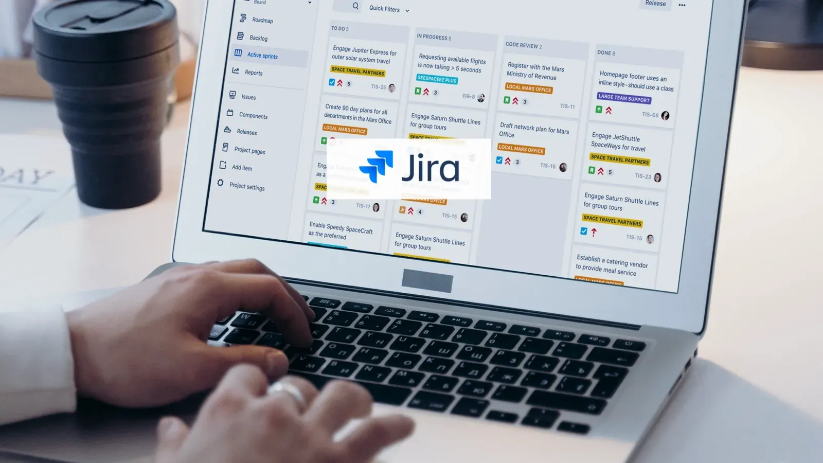 A person is typing on a laptop computer with a jira logo on the screen.